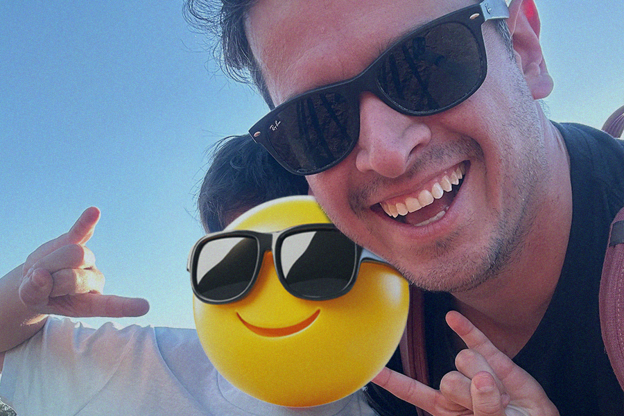 a man wearing sunglasses next to a large three dimensional emoji also with sunglasses. 