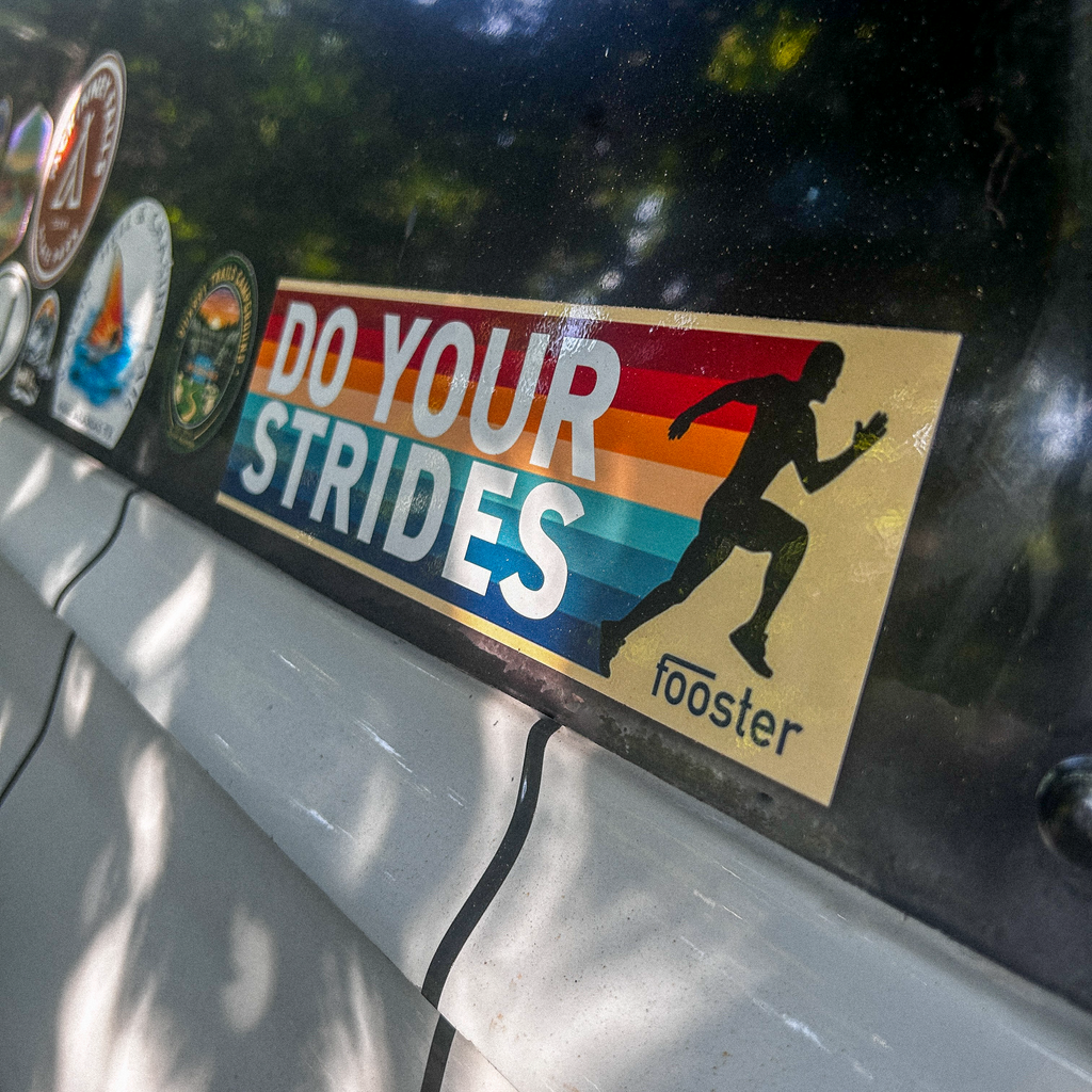 Sticker with 'Do Your Strides' text on a car window with other stickers.