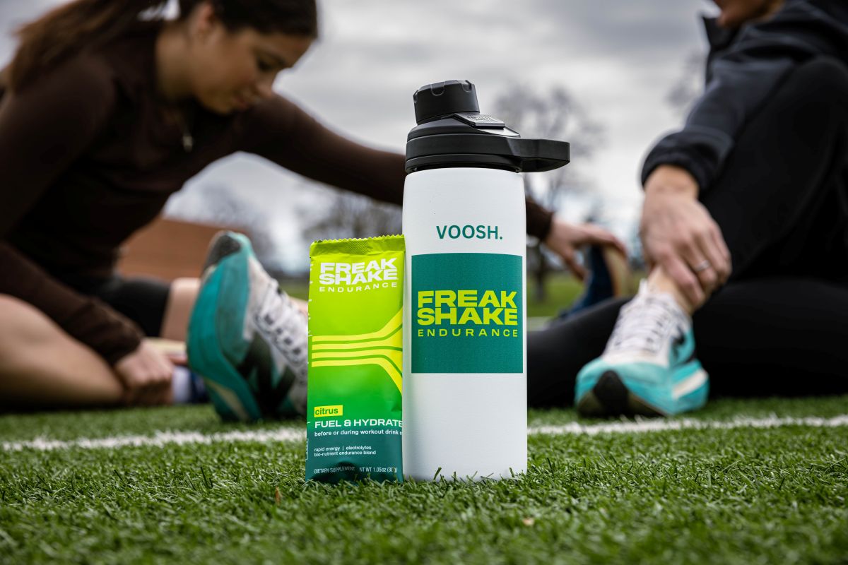 VOOSH Freak Shake Endurance bottle and packaging on grass with people in the background