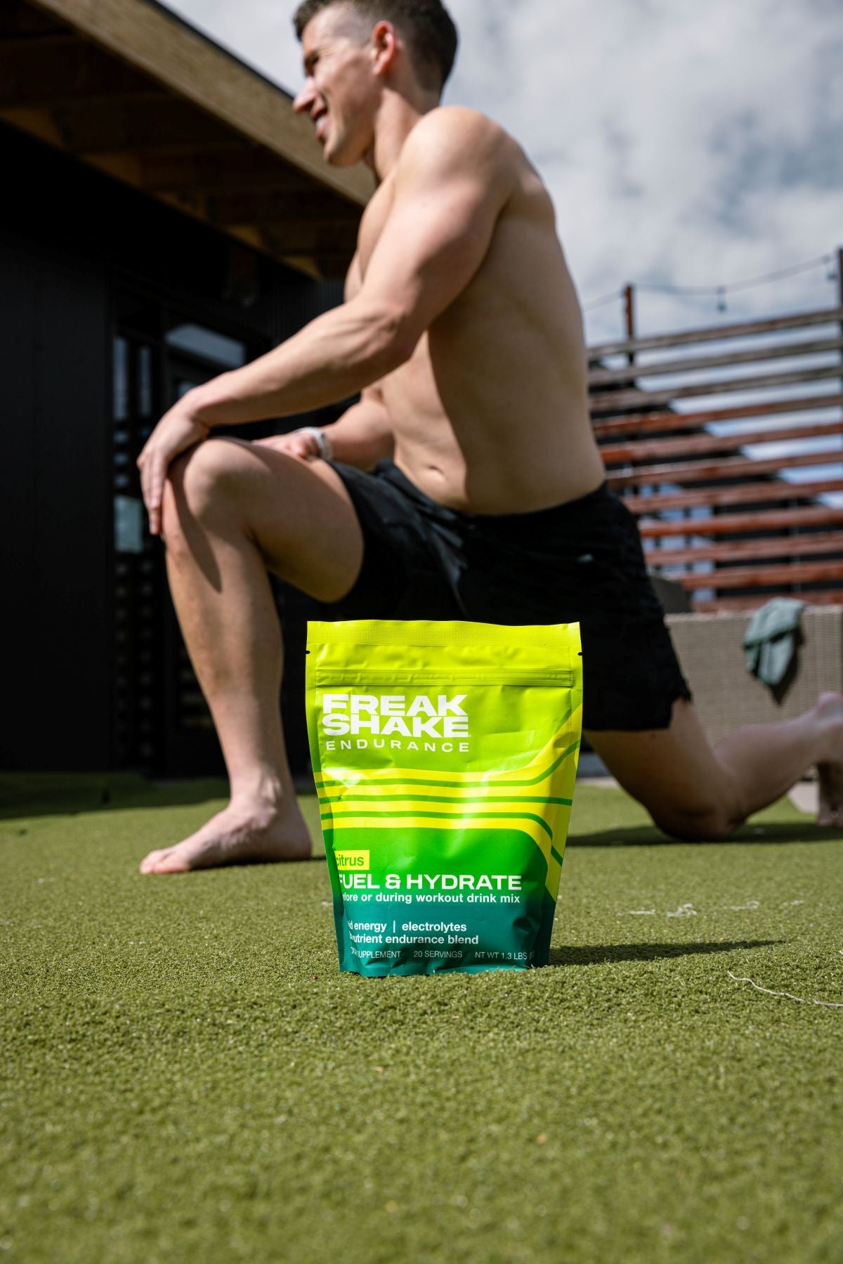 Man sitting on grass with a 'Freak Sport Endurance' supplement package in front of him.