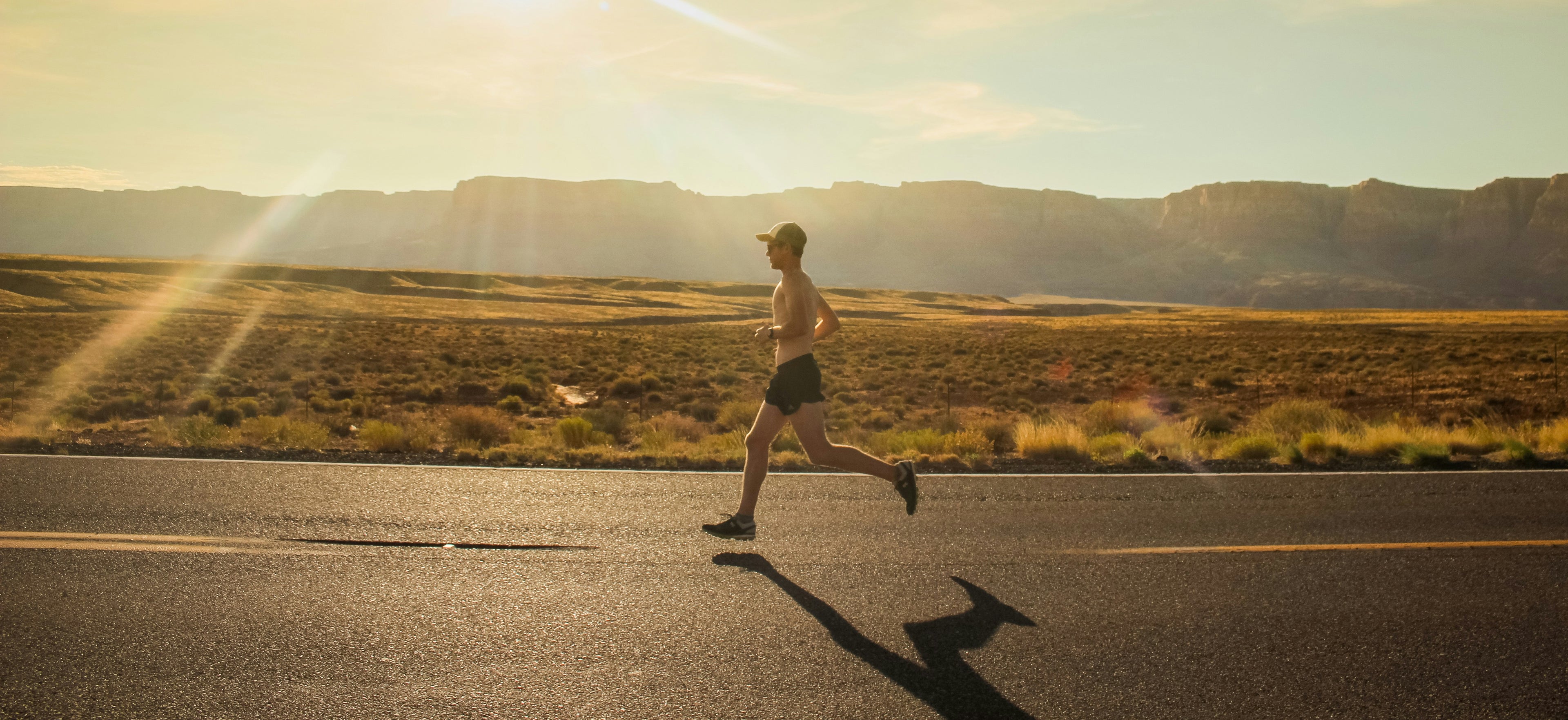 Person running on a road with mountains in the background
