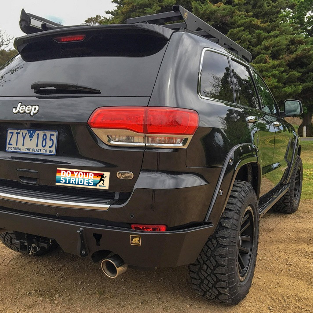 Black Jeep with off-road tires and a roof rack in a natural setting