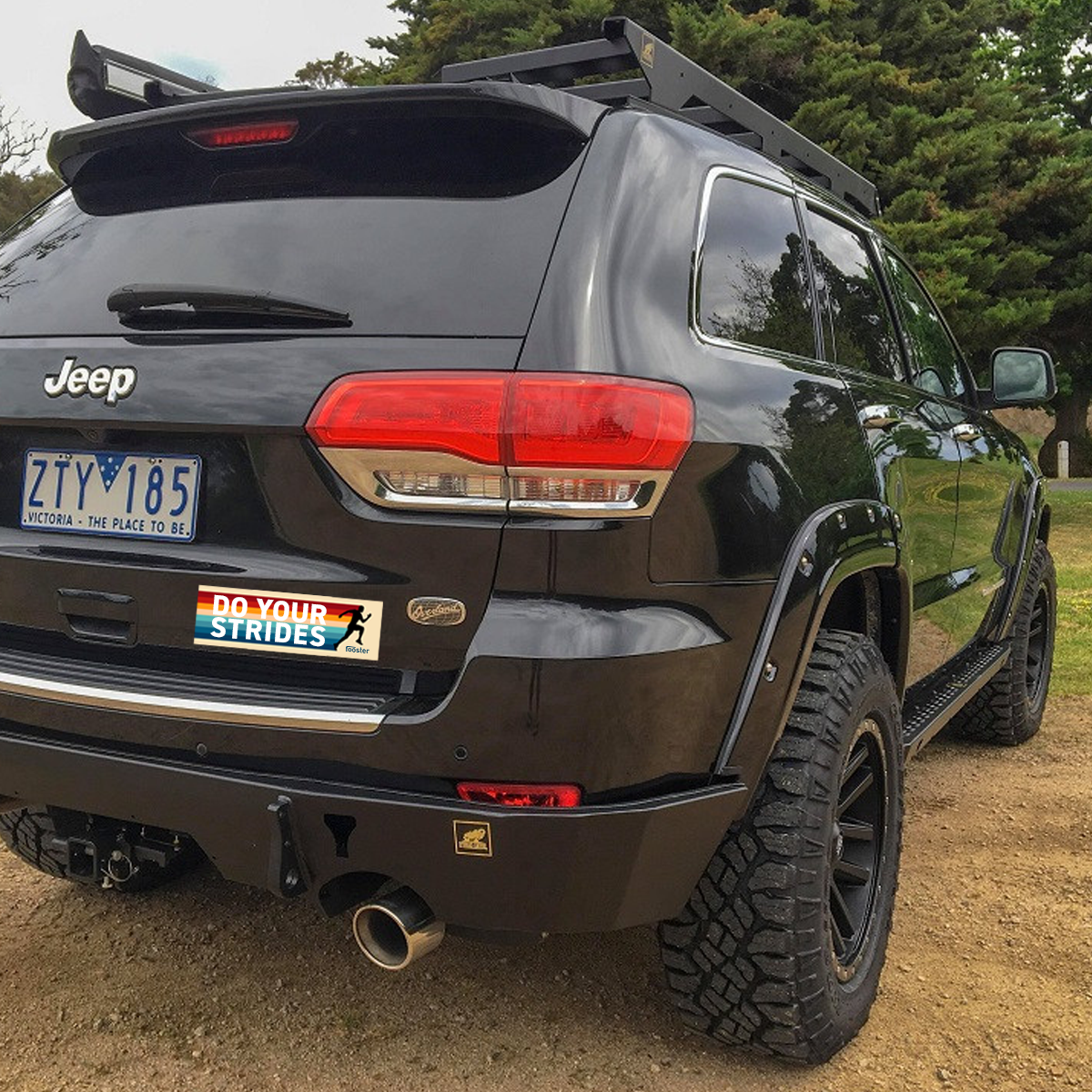 Black Jeep with off-road tires and a roof rack in a natural setting